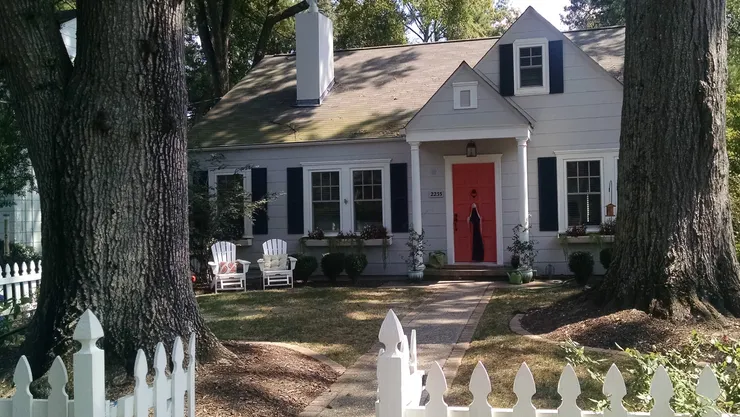 a white house with a red door and a white picket fence