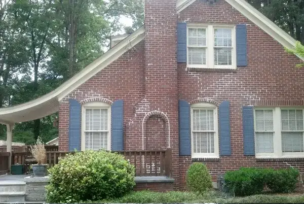 a red brick house with blue shutters and a white awning